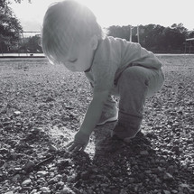 a toddler boy playing in gravel 