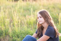 teen girl sitting outdoors thinking 