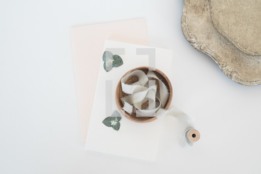spool of ribbon in a wooden bowl, stationary, and silver tray 