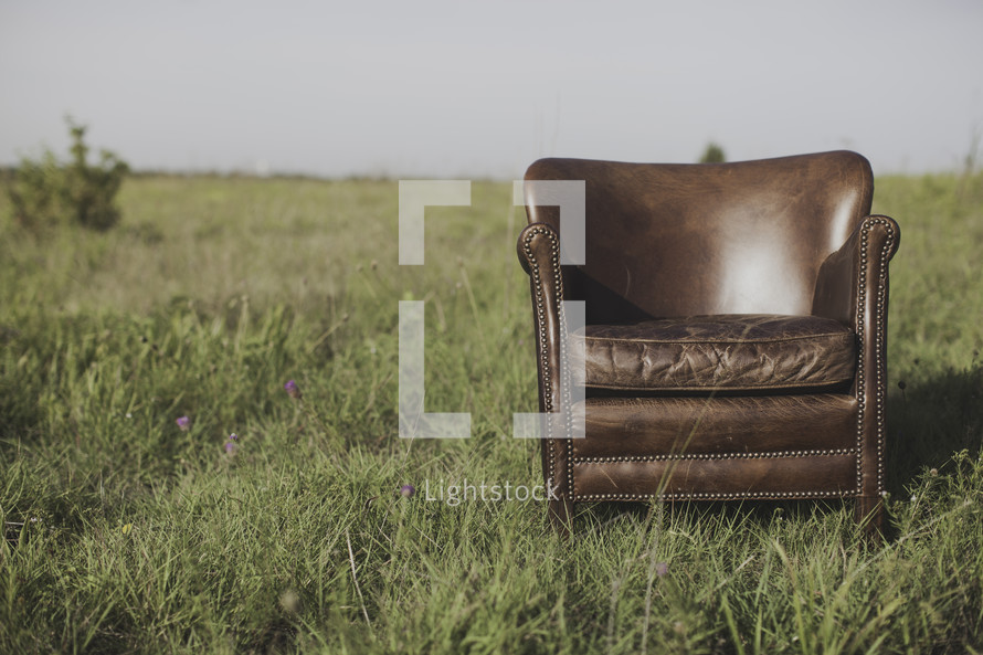 a leather chair alone in a field 