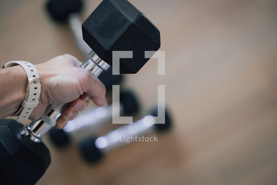 Woman's hand picking up dumbbells