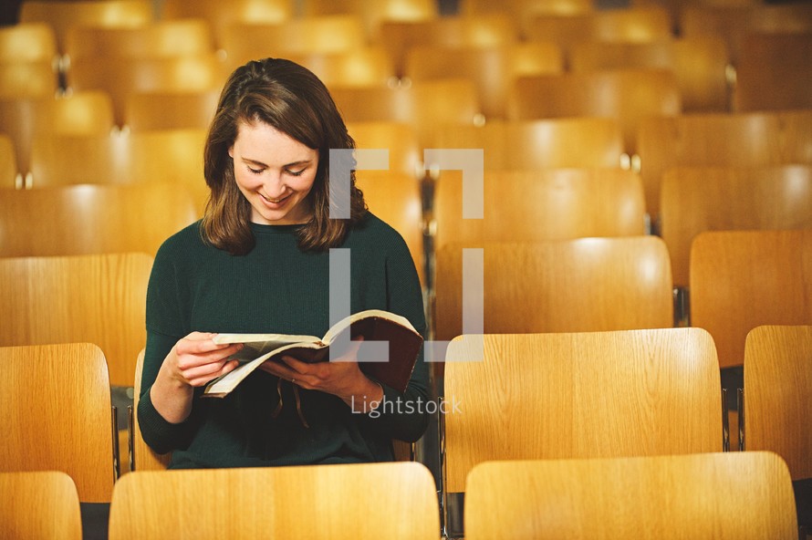 a woman reading a Bible alone in a church 