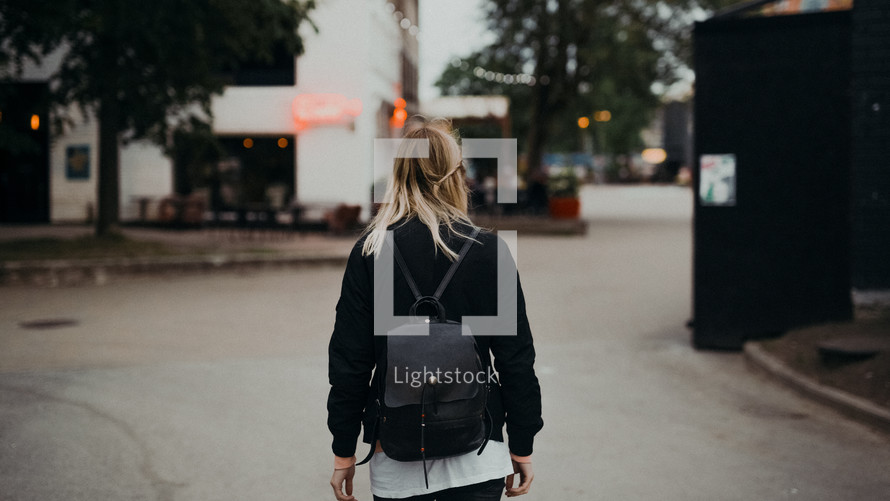 a young woman walking towards an outdoor restaurant 