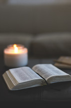 open Bible and candle on an ottoman 