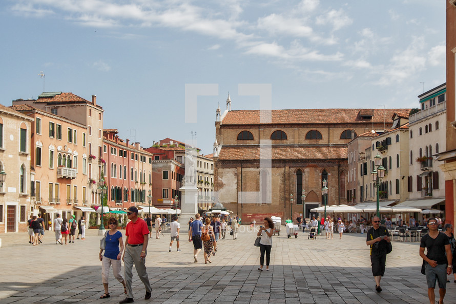 pedestrians walking through a town square in Venice 