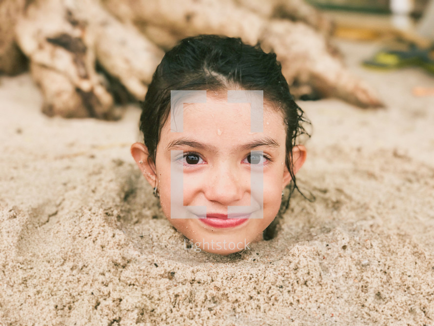 a little girl buried in the sand 