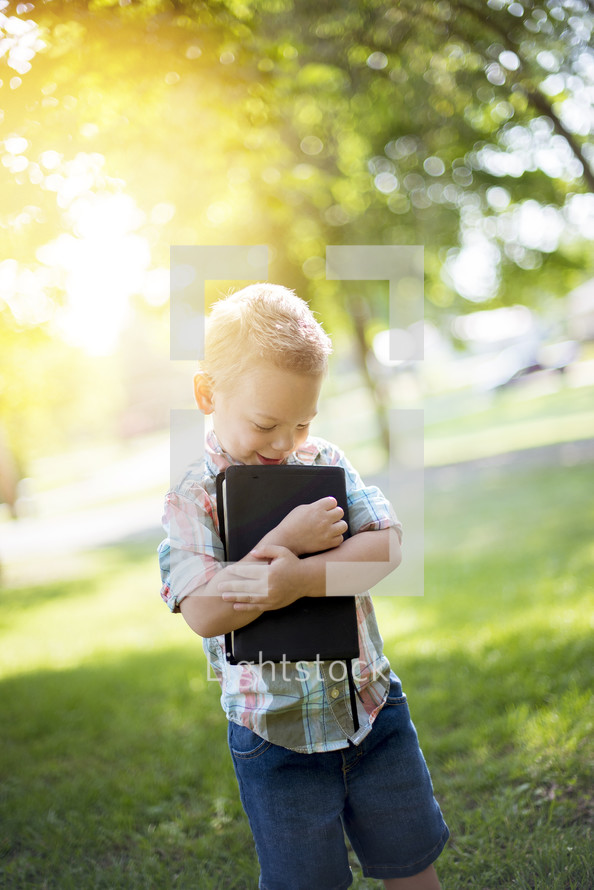 toddler boy hugging a Bible to his chest 
