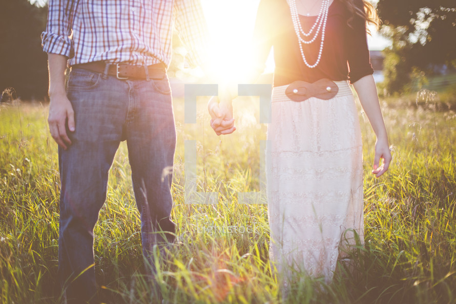 a couple holding hands standing in a field 