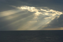 Sun beaming through clouds on ocean. The heavens declare the glory of God!
