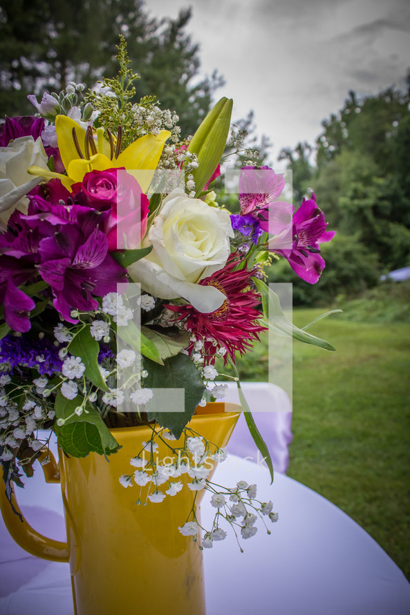 flower arrangement in a yellow pitcher on a table 
