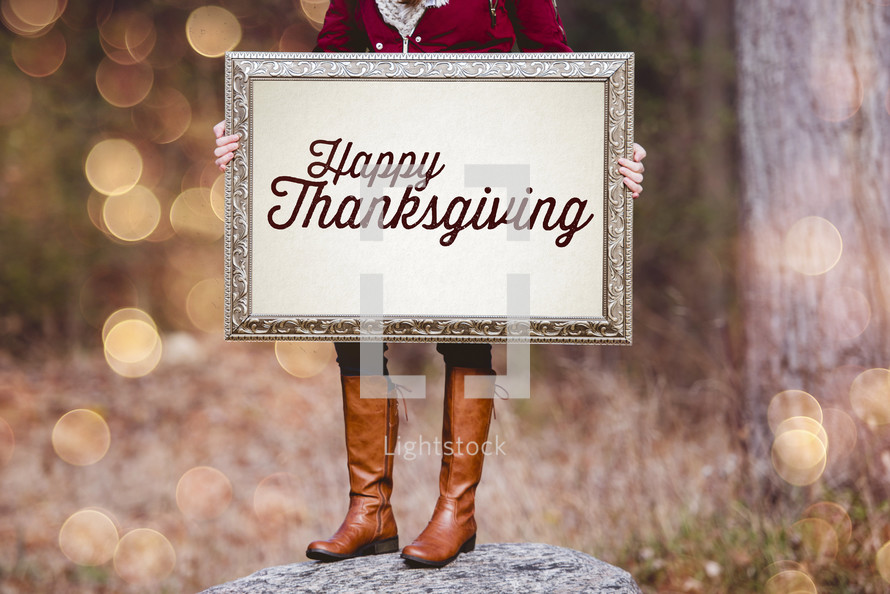 a woman holding a sign the reads Happy Thanksgiving 