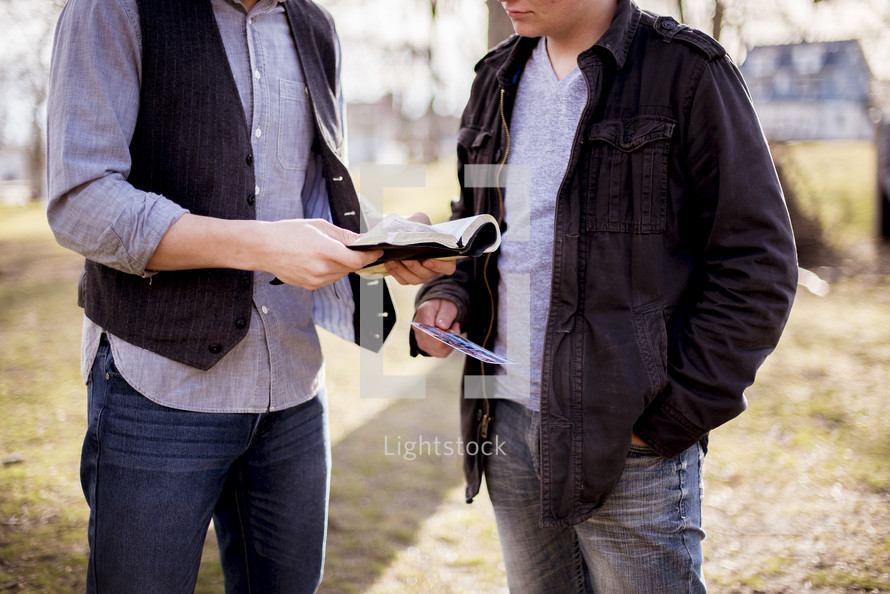 two men reading Bibles outdoors 