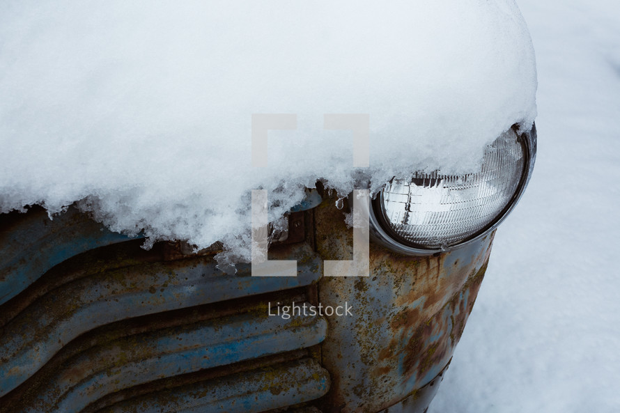A vintage pickup truck headlight in the snow