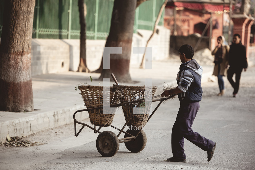 a man pushing a cart down a street 