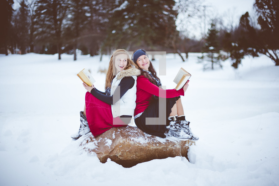 two women reading Bibles outdoors in snow 