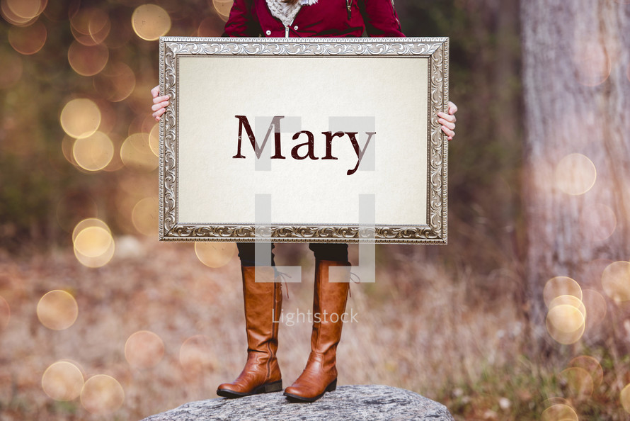 a woman holding a sign the reads Mary 