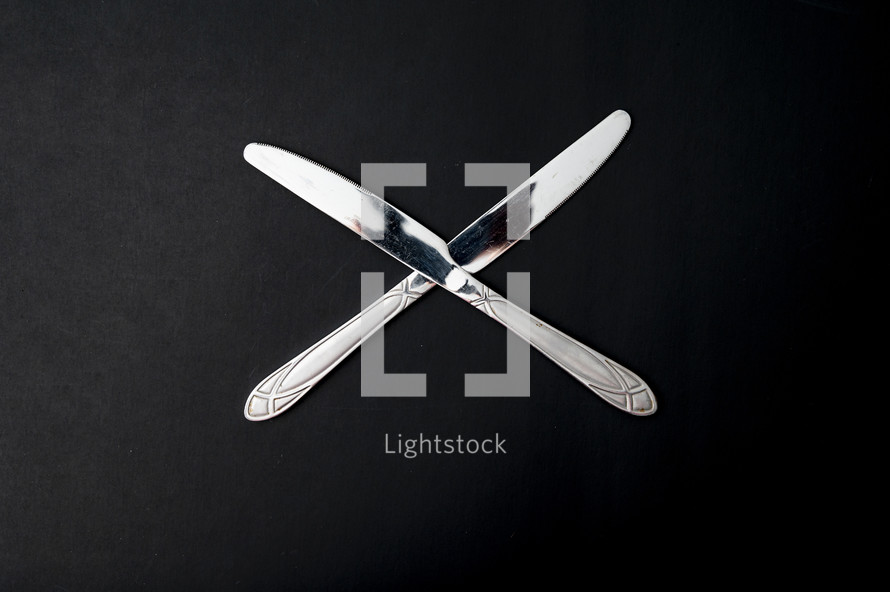 two butter knives on a black background 