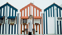 woman walking in front of striped beach houses 