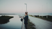 a woman standing near a boat ramp looking out at the water 