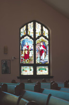 pews in a church and stained glass window of Jesus 