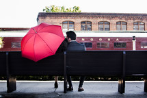 a couple snuggling under a red umbrella 