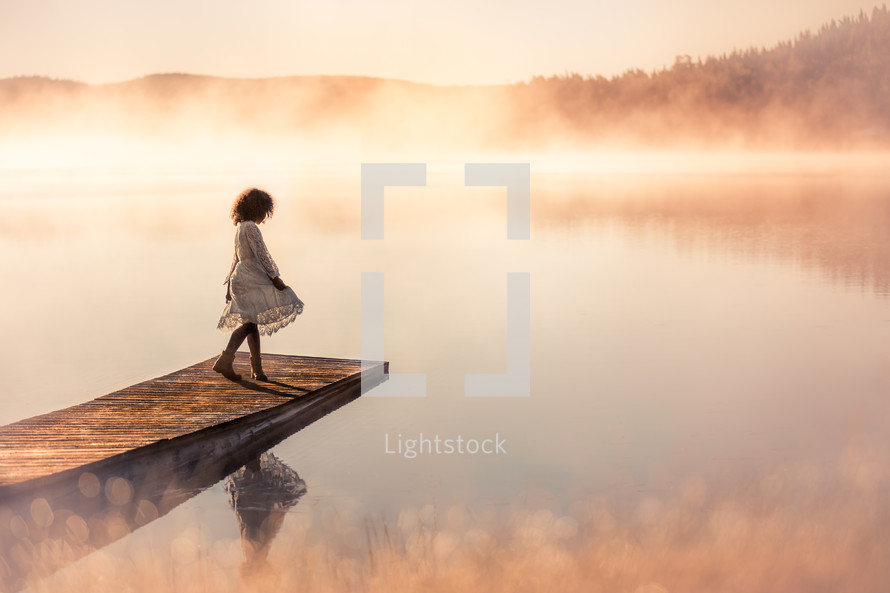 girl on a dock over a steaming lake at sunrise 