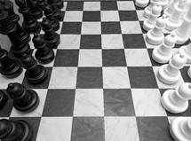 A black and white image of a huge chess board with chess pieces in black and white on a checkered black and white chess board that takes up about 10 feet of floor space symbolizing the game of life, life and death, good and evil, risk and chance and strategy and planning. All the things that make up life and thinking through moves that we make that can affect our spiritual and physical as well as mental well being. 

I saw this huge chess board at a local shopping mall and it just captured my imagination and had to photograph it. It reminded me of the game of life and the choices we have to make to affect our future as well as the spiritual battle between good and evil that we deal with in this life and the next. 