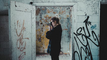 a woman taking a picture in an abandoned building covered in graffiti 