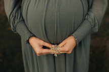 a pregnant women holds a flower in front of her belly