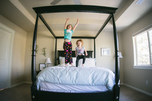 sisters jumping on a bed 