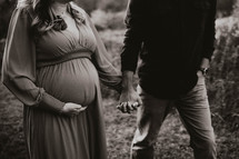 a pregnant woman and her husband hold hands