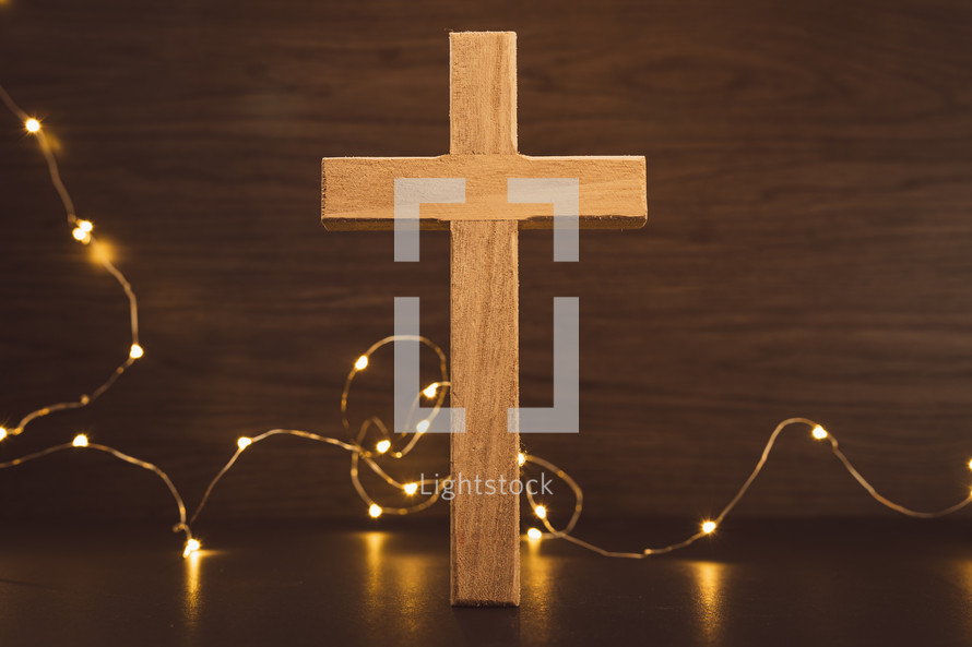 Wood cross and mini lights on a dark wood background
