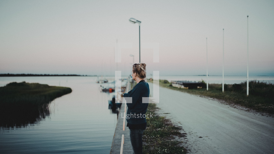 a woman standing near a boat ramp looking out at the water 