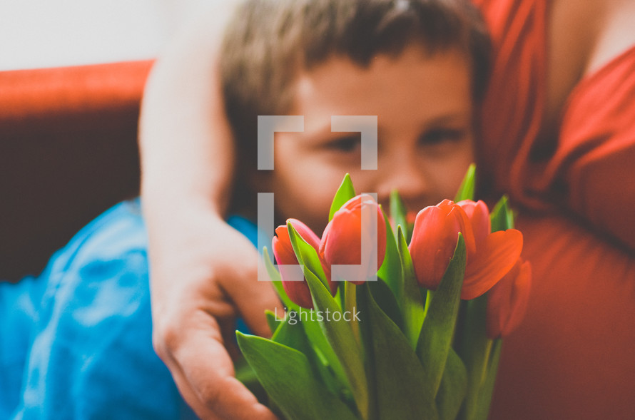 a boy giving his mother flowers for mother's day