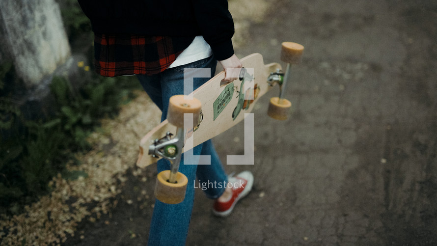 a teen girl carrying a skateboard 