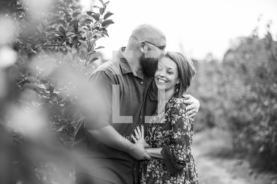 a couple hugging in an orchard 