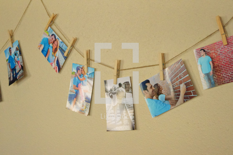 Snapshots of people, clothes pinned to a string on a wall