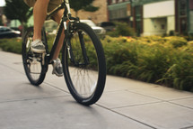 a man on a bicycle riding down a sidewalk. 