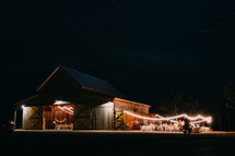 An old barn lit by strings of lights for a party.