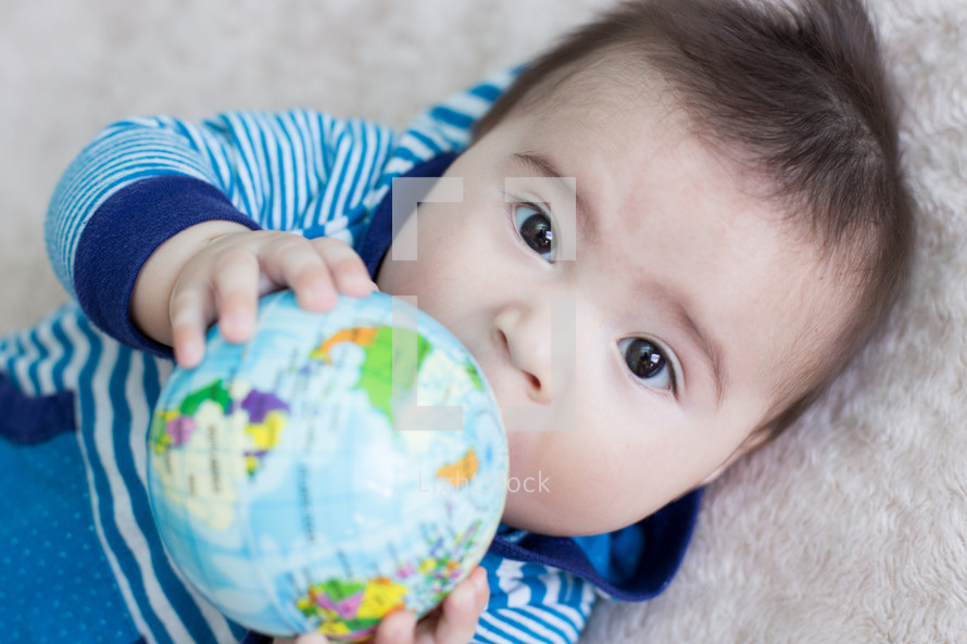 Infant child holding a globe ball.