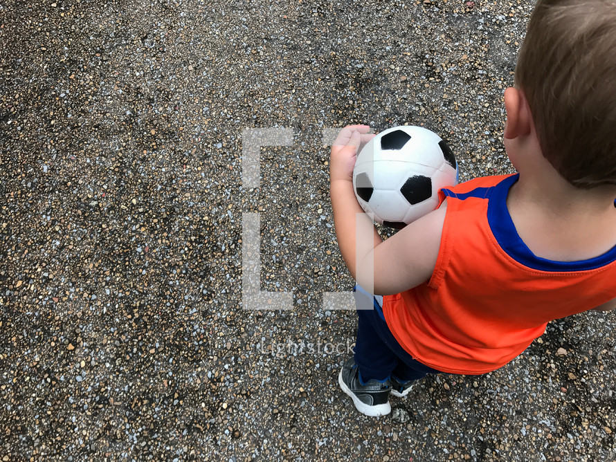a boy carrying a soccer ball 