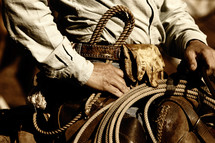 An authentic working cowboy in the American West rides to work on his horse in sunset light (sepia/brown tint).
