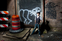 boy standing in an alley next to a construction cone