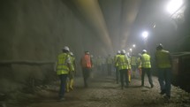Construction workers walking out from a dark smoke filled tunnel