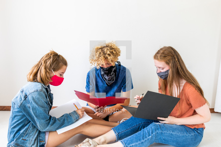 teens doing school work in face masks 
