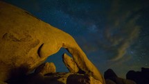 Timelapse of Milky Way galaxy stars rising over Arch Rock with clouds rolling by in the night sky.   This time-lapse was filmed in Joshua Tree National Park. 