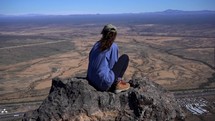 A young woman taking in the view from the top of a mountain