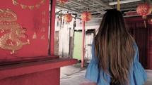 a young woman walking through an Asian market 