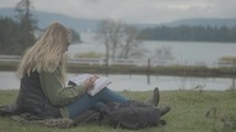 Young woman reading and studying the Bible outside.