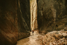 woman hiking through a river in a canyon 